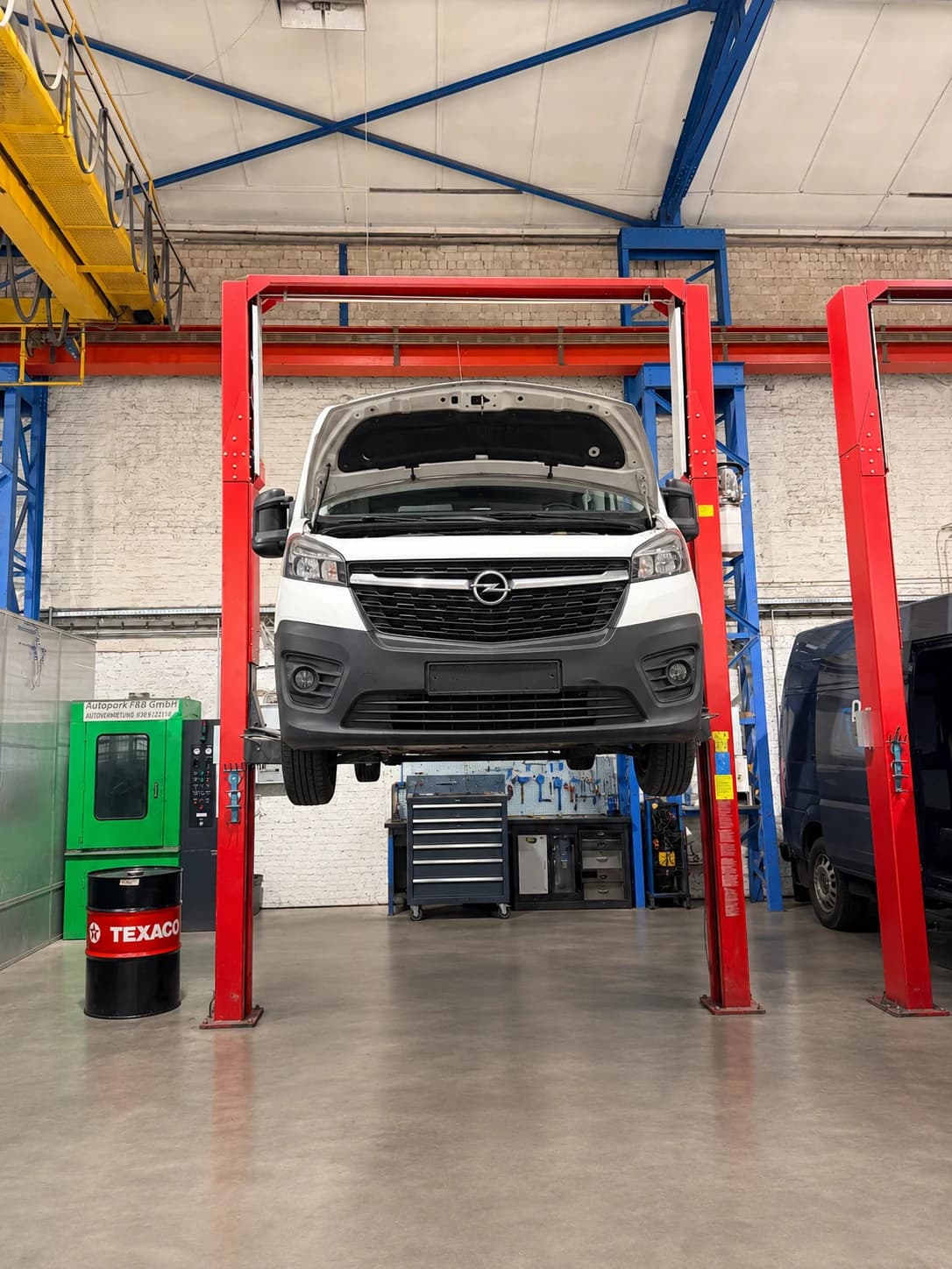 Sauberer Transporter steht mit geöffneter Motorhaube auf einer Werkstatthebebühne