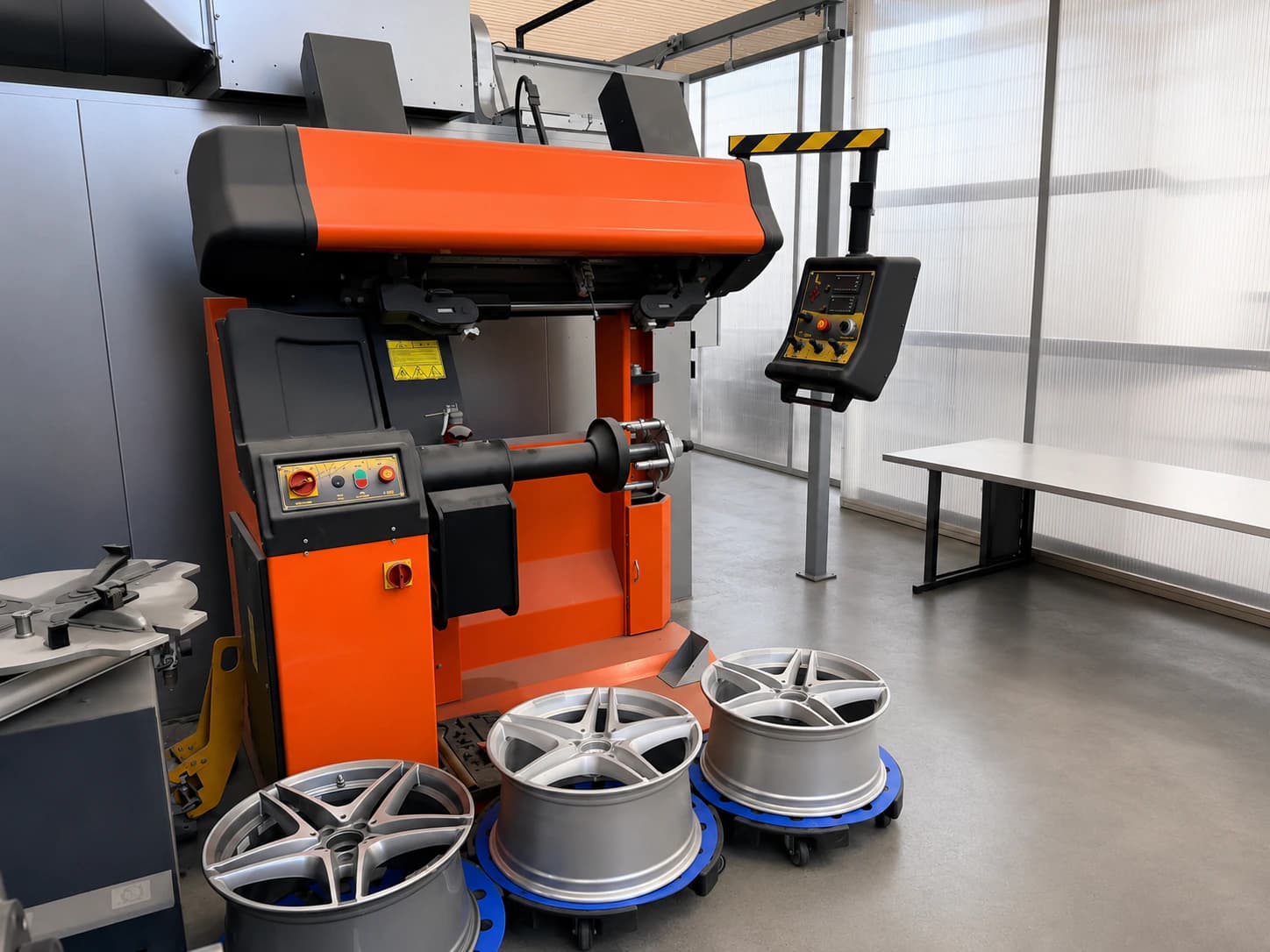 Orange Felgenrichtmaschine mit mehreren Aluminiumfelgen im Arbeitsbereich